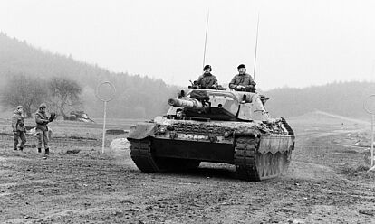 Frontansicht eines Kampfpanzers Leopard 1 in Fahrt auf einem Übungsgelände der Bundeswehr. Aus einer Turmlucke schaut Bundeskanzler Helmut Kohl.