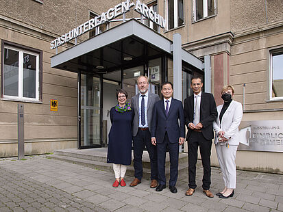 Kim Yung Ho und Mitarbeiter des Bundesarchivs stehen vor dem Eingang zum Stasi-Unterlagen-Archiv.