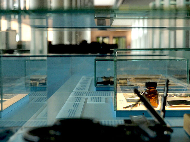 Ausstellungsvitrine mit fotografischen Materialien durch Glas fotografiert und mehrfach gespiegelt.