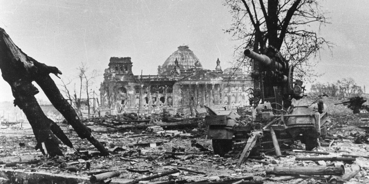 Zerstörter Reichstag in Berlin Blick über den entbaumten Tiergarten auf den zerstörten Reichstag. Im Vordergrund steht eine zerstörte 8,8-cm-Flak 18/36/37, Quelle:
BArch, Bild 183-J0422-600-007 (Ausschnitt) / o. Ang.