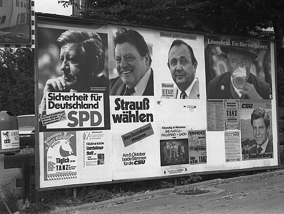 Mehrere Wahlplakate, die unter anderem Helmut Schmidt, Franz Josef Strauß und Hans-Dietrich Genscher zeigen.