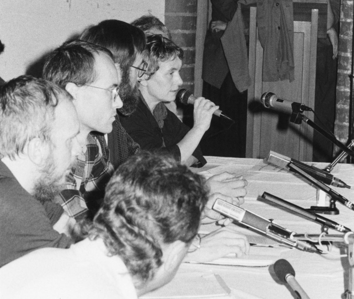Mitglieder des Neuen Forums sitzen auf dem Podium während einer Veranstaltung in der Berliner Christuskirche. Die Bürgerrechtlerin Bärbel Bohley (Mitte) spricht in ein Mikrofon. 