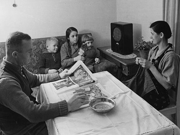 Familie im Wohnzimmer beim Radiohören mit Volksempfänger, Typ VE 301 (1933/1943 ca.)