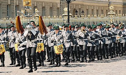 Mehrere Soldaten der Bundeswehr marschieren mit verschiedenen Instrumenten am Schloss Charlottenburg vorbei.