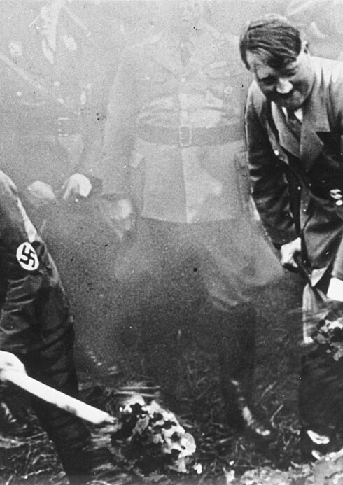 Adolf Hitler und ein weiterer Mann mit Hakenkreuz-Emblem auf dem Jackenärmel schippen Sand mit einer Schaufel auf einen Haufen. Das Bild wurde am 23. September 1933 beim Spatenstich zum Reichsautobahnbau bei Frankfurt/Main aufgenommen.