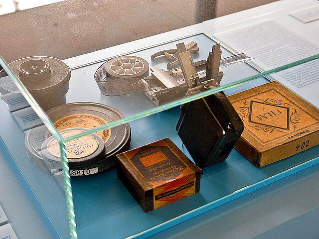 In einer flachen Glasvitrine liegen Faksimiles von historischen Objekten.