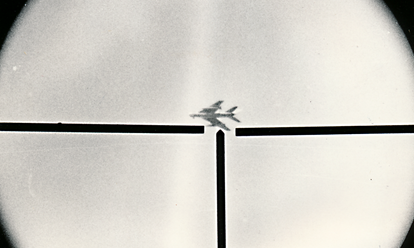 Foto, auf dem ein Flugzeug am Himmel zu sehen ist, das sich im Fadenkreuz einer Waffe befindet.
