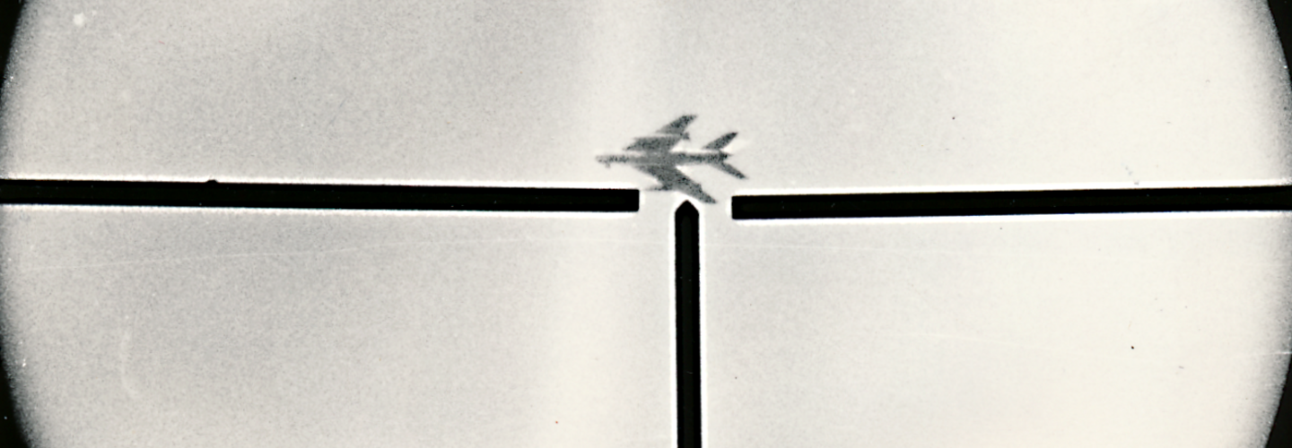 Foto, auf dem ein Flugzeug am Himmel zu sehen ist, das sich im Fadenkreuz einer Waffe befindet.