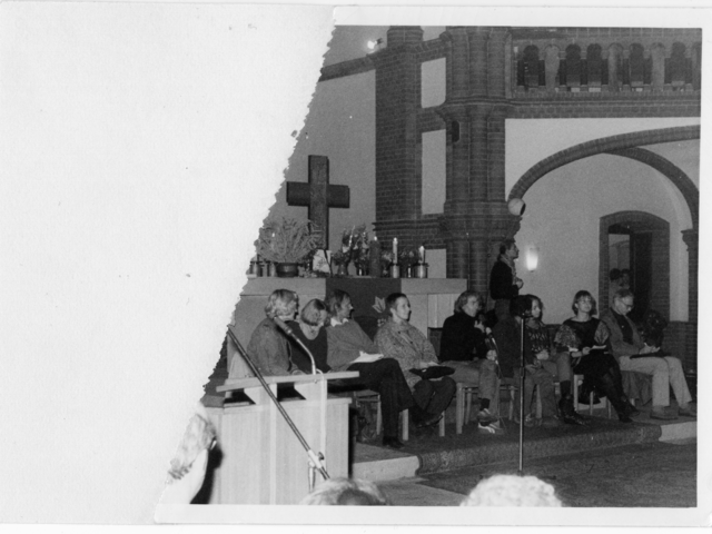 Ein Fotofragment, das die Teilnehmerinnen und Teilnehmer einer Diskussionsrunde in der Gethsemanekirche zeigt. Unter dem Altarkreuz ist der Theologe Erhart Neubert mit einem Zettel auf dem Schoß zu sehen und am Mikrofon Pfarrer Bernd Albani. Links daneben die Bürgerrechtlerinnen Katja Havemann und Angelika Barbe und rechts außen Marianne Birthler und der Molekularbiologe Jens Reich.