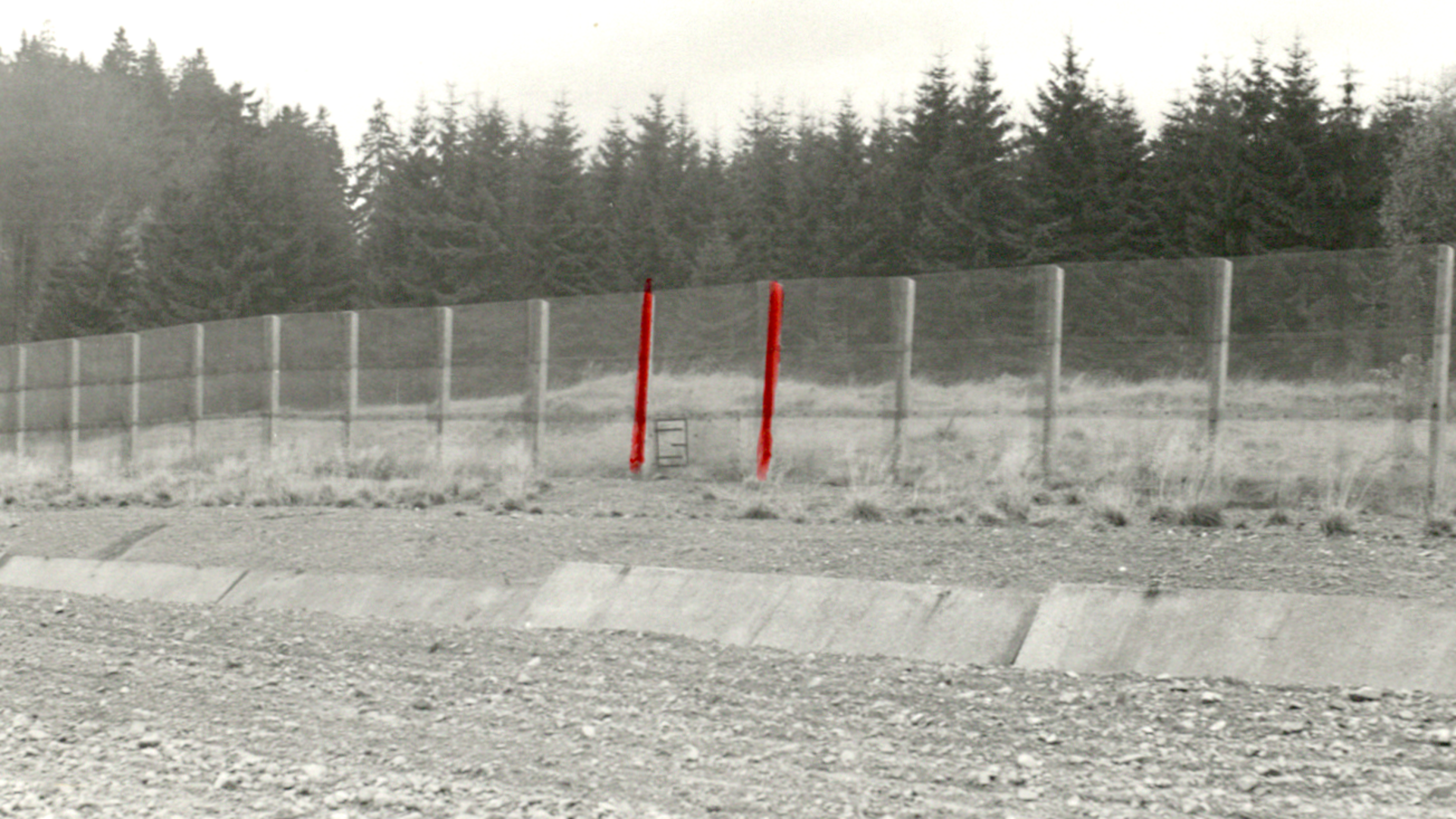 [In den Grenzsicherugsanlagen wurden Kfz-Sperrgraben und Grenzzaun fotografiert. Da das Schlupftor im unteren Drittel des Grenzzauns nicht zu erkennen ist, wurde es mit Bleistift extra eingezeichnet, die beiden umgebenden Zaunpfeiler wurden mit rotem Filzstift nachgemalt.