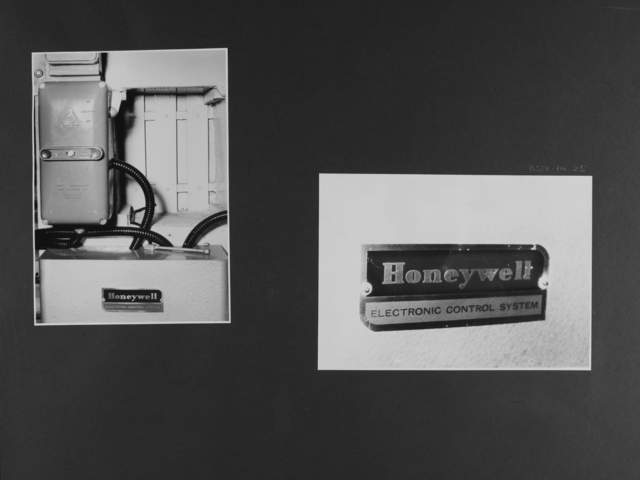 [Bild 1: Ein Kunststoffgehäuse, aus dem ein schwarzer Schlauch tritt, dessen Windungen im Hintergrund zu erkennen sind, hängt über einem Metallkasten mit dem Markenschild "Honeywell".]  [Bild 2: Nahaufnahme des Markenschildes:  Honywell Electronic control system]