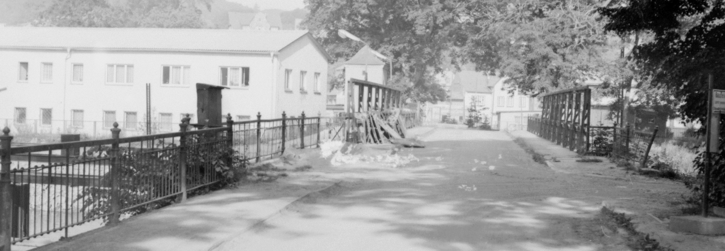 Aufnahme auf einer Brücke mit Blick auf mehrere Häuser und Sperrgut am Rand