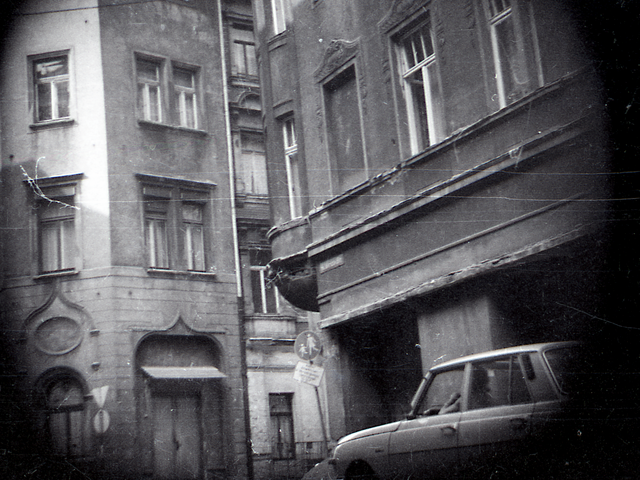 Das Foto ist mit versteckter Kamera entstanden und zeigt ein Eckhaus. Die Eingangstür und das Fenster im Erdgeschoss sind mit Rundbögen und orientalischen Verzierungen versehen. Am Straßenrand parkt ein Pkw.