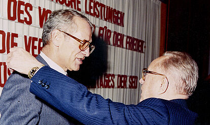 Erich Mielke verabschiedet Markus Wolf aus dem aktiven Dienst. Die beiden Männer reichen sich die Hände. Mielke legt dabei seine linke Hand auf Wolfs Schulter.