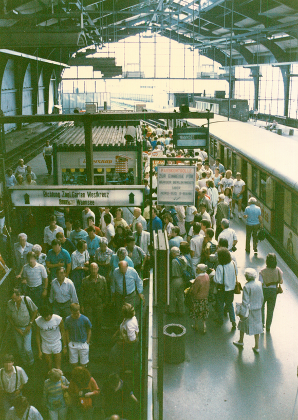 Menschen auf dem Bahnsteig. Am rechten Bildrand ist eine S-Bahn zu sehen.