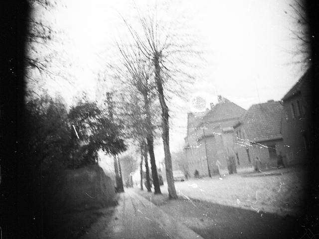 Vom Gehweg der Gattersleber Straße in Nienburg (Saale) aufgenommenes Schwarz-Weiß-Foto mit Häusern, Fußgängern und Autos im Hintergrund.